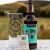 HOPO Session IPA with Broughton Ales glass and metal bottle opener against background of Scottish borders scenery